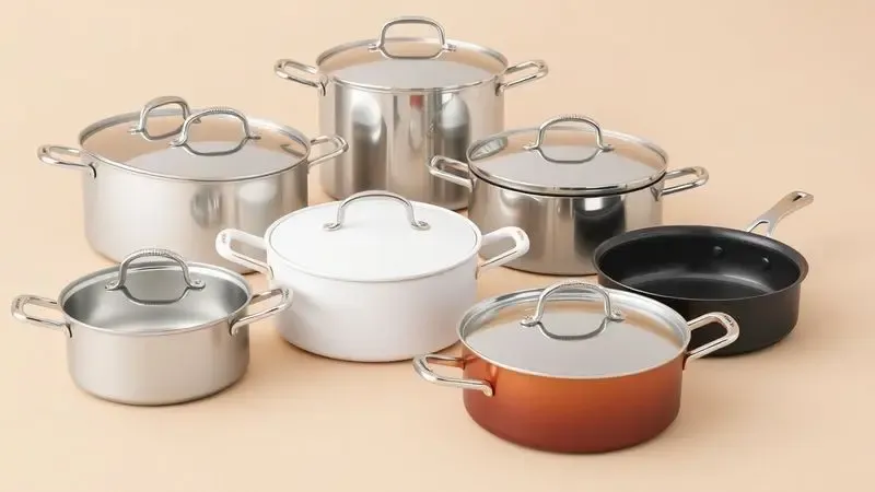Conjunto de panelas de diferentes materiais em uma superfície limpa, ilustrando a diversidade de utensílios de cozinha.