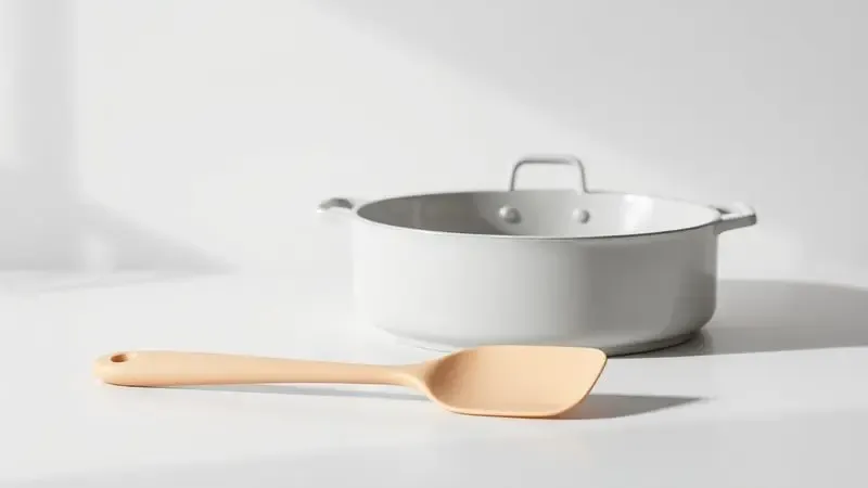Espátula de silicone repousando ao lado de uma panela de cerâmica limpa, simbolizando o uso de utensílios corretos.
